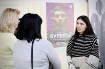 Жінки ведуть діалог у приміщенні, поруч документи на столі.