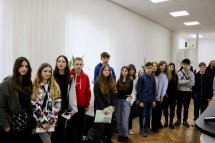Група людей стоїть у черзі в коридорі.