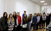 Група людей стоїть у черзі в коридорі.
