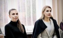 Дві жінки в діловому одязі дивляться вбік.