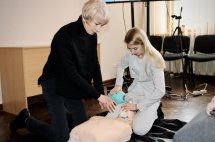 Навчання з надання першої допомоги: жінка проводить серцево-легеневу реанімацію на манекені.