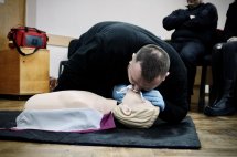 Чоловік проводить штучне дихання на медичному манекені.