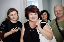 Жінки та чоловік усміхаються, одна з жінок тримає телефон.