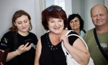 Жінки та чоловік усміхаються, одна з жінок тримає телефон.