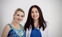 Дві жінки усміхаються, позуючи перед камерою.