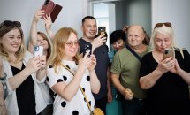 Група людей посміхаються та фотографують на телефон.