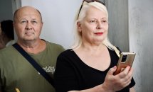 Жінка з телефоном у руках стоїть поруч із чоловіком.