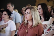 Люди стоять із серйозними виразами обличчя, поклавши руку на серце.