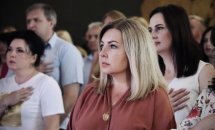 Люди стоять із серйозними виразами обличчя, поклавши руку на серце.