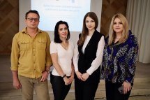 Троє жінок та чоловік позують перед камерою у приміщенні.