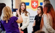 Жінки спілкуються біля банера.