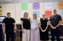 Група людей позують з сертифікатом у руках.