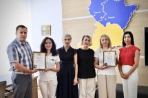 Група людей позують з сертифікатом у руках.