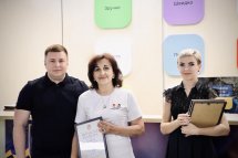 Чоловік у чорній футболці разом із двома жінками демонструють сертифікати.