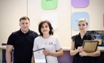 Чоловік у чорній футболці разом із двома жінками демонструють сертифікати.