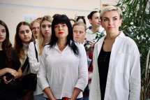 Група дівчат у діловому одязі стоїть у приміщенні.