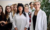 Група дівчат у діловому одязі стоїть у приміщенні.