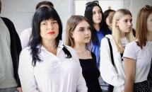 Група дівчат у діловому одязі стоїть у приміщенні.