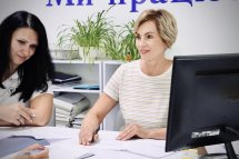 Дві жінки працюють за столом, переглядаючи документи.