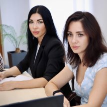 Дві жінки сидять у приміщенні.