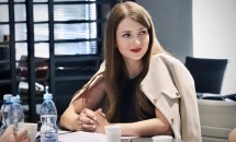 Жінка в бежевому піджаку уважно слухає під час обговорення.
