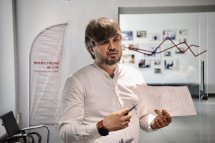 Чоловік із бородою проводить презентацію, тримаючи документ.