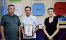 Два чоловіка і жінка з сертифікатом позують для фото.