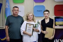 Жінки з грамотами та нагородами на фоні кольорової стіни.