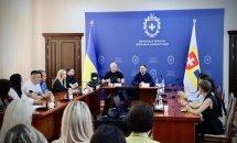 Офіційна зустріч у залі, люди сидять за столами.