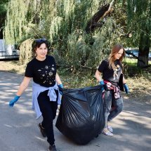 Волонтери працюють разом, збираючи сміття в чорні мішки.