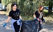 Волонтери працюють разом, збираючи сміття в чорні мішки.