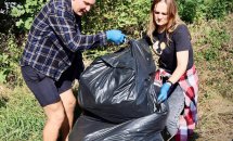 Двоє людей наповнюють мішок зібраним сміттям.