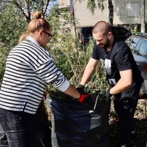 Двоє людей наповнюють мішок зібраним сміттям.