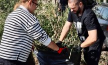 Хлопець та дівчина наповнюють мішок зібраним сміттям.