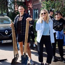Хлопець тримає в руках лопати. Біля нього стоїть жінка і усміхається.