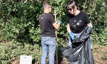 Двоє людей наповнюють мішок зібраним сміттям.