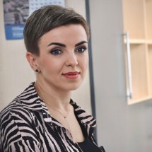 Жінка з короткою зачіскою усміхається та дивиться в камеру.