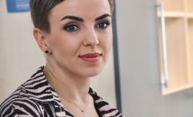 Жінка з короткою зачіскою усміхається та дивиться в камеру.