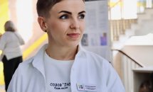 Жінка з короткою зачіскою привітно посміхається.