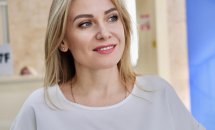 Жінка з світлим волоссям привітно посміхається.