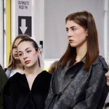 Дві дівчини уважно слухають екскурсовода.