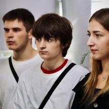 Молоді люди стоять разом, уважно слухаючи.
