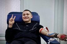 Чоловік-донор у кріслі для донації показує жест "мир".