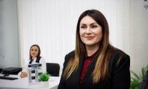 Працівниця ЦНАПу усміхається, сидячи за робочим місцем.
