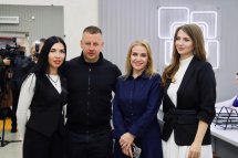 Група людей стоїть перед логотипом установи, позуючи для фото.