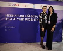 Дві жінки позують на фоні банера з написом "Міжнародний форум інституцій розвитку".