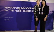 Дві жінки позують на фоні банера з написом "Міжнародний форум інституцій розвитку".