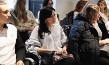 Учасники конференції сидять у залі, серед них жінки в білих та темних піджаках.