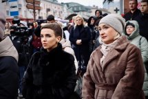 Дві жінки у теплому одязі стоять серед натовпу людей, на задньому плані – камери та журналісти.