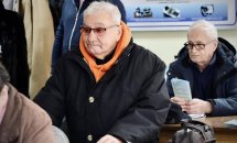 Літні чоловіки в окулярах беруть участь у заході, тримаючи в руках роздаткові матеріали.
